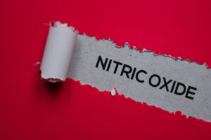 The word nitric oxide revealed under torn red paper, representing blood flow and circulation.
