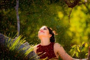 Woman outdoors surrounded by floating pollen, representing natural relief from allergies through quercetin and vitamin C.